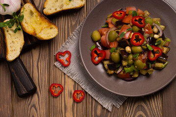 Traditional Sicilian dish of eggplant caponata on a wooden table. Top view