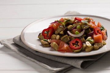 Traditional Sicilian dish of eggplant caponata, in a plate, on a wooden table