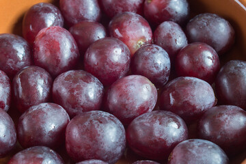 Close-up of a bunch of black grapes in a clay jar. Healthy fruit as an alternative to bite to eat and appetizers.