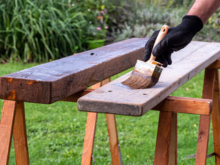 Hand of a male painter with a paint brush in his hands. A man, Caucasian, paints a wooden terrace. Painting works