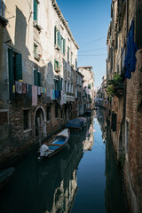 Narrow canals with bridge of Venice, Italy. Tourist sailing on an romantic gondola with gondolier boat. Exterior of medieval buildings.