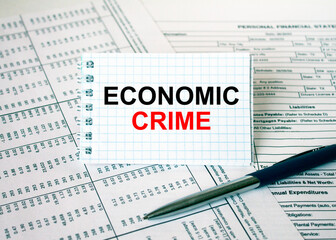 Obraz premium Notepad with text Economic Crime lying on financial tables with a pen