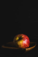 MANZANA ROJA Y AMARILLA GOLDEN SOBRE PLATO DE MADERA Y FONDO NEGRO