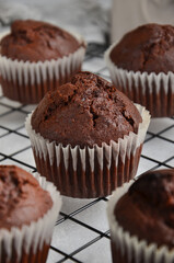 Chocolate muffins on a black metal grill on a gray background.