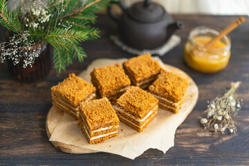 Layer Honey sliced Cake with pastry cream filling on wooden cutting board, dark wooden table near window. Close up view, copy space. Organic homemade dessert.