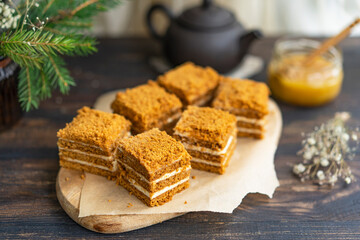 Layer Honey sliced Cake with pastry cream filling on wooden cutting board, dark wooden table near window. Close up view, copy space. Organic homemade dessert.