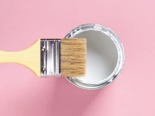 Close-up of new natural bristle brush with wooden handle on an open white paint can over pastel...