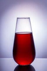 Drop-shaped glass container with red liquid inside