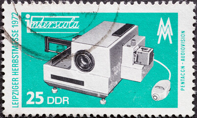 Obraz premium GERMANY, DDR - CIRCA 1972: a postage stamp from Germany, GDR showing a slide projector. Text: Leipzig Autumn Fair 1972