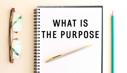 Notepad with text WHAT IS THE PURPOSE on a white background, near glasses and pencil.