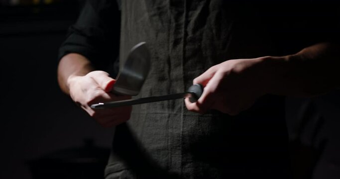 Professional chef is sharpening his knife before cooking a meal. Cool cooker is preparing his tools - food cooking concept close up 4k footage