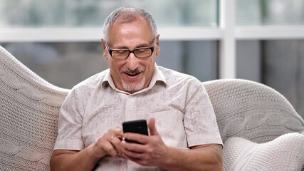 Happy 70s grandfather winner mobile app sport bet holding smartphone. 4k Dragon RED camera