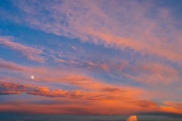 Background of amazing mystery red and yellow clouds illuminated by rays of evening sun on blue sky at sunset. Telephoto lens photo shot