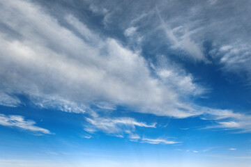 Beautiful blue sky background at daylight with white streched spindrift clouds. Wide angle photo shot