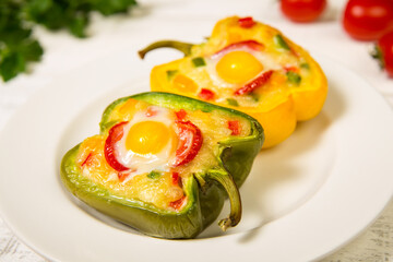Fototapeta na wymiar Bell peppers stuffed with vegetables, baked with cheese and quail eggs in a white plate. Selected focus. Close-up.