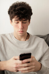 chico en el sofá escribiendo un mensaje en su celular movil