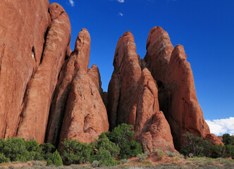 Red Rock Spires In The Arches National Park Utah On A Sunny Summer Day With A Clear Blue Sky And A Few Clouds