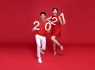 Fototapeta na wymiar Happy asian couple showing number 2021 greeting happy new year with smiles on bright red background.