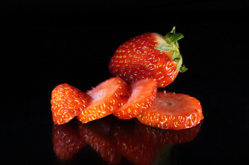 Whole and split strawberry on black background