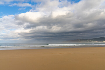 empty and large beautiful golden sand beach underneath a bad weather sky