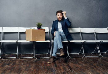 disgruntled man sitting on chairs with a box job search