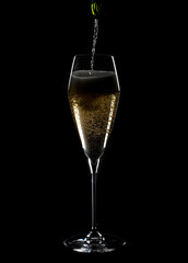 Pouring Champagne into a Lead Crystal Flute Back Lit and Isolated on Black Background