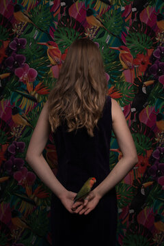 Girl with her lovebird apagornis in decor of wildlife