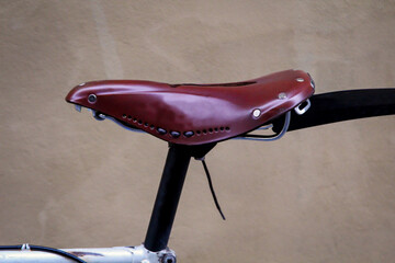 Ein lederner Fahrradsitz auf der Sattelstange eines Fahrrades. - obrazy, fototapety, plakaty