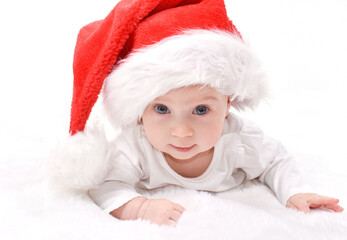 Christmas mood, baby. Cute four month old caucasian baby in a red Santa Claus hat lying on stomach, looking at camera and smiling, on a white background. Christmas Card.