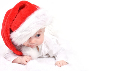 Christmas mood, baby. Cute four month old caucasian baby in a red Santa Claus hat lying on stomach, cunning look, leer, on a white background. Copy space. Christmas and New Year card.