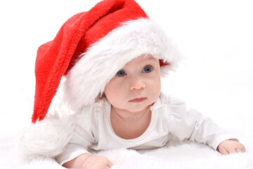 Christmas mood, baby. Cute four month old caucasian baby in a red Santa Claus hat lying on stomach, on a white background. Christmas card.