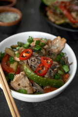  Soba noodles with chicken, hot pepper, zucchini, mushrooms, green onions on the  dark  background. Selective focus. Asian food