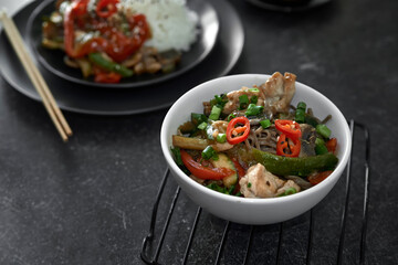  Soba noodles with chicken, hot pepper, zucchini, mushrooms, green onions on the  dark  background. Selective focus. Asian food