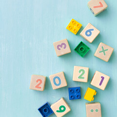 Colorful plastic and wooden cubes with numbers scattered on a blue wooden table. Top view of children's toys and other equipment. Educational games for children. Cubes with numbers 2021.