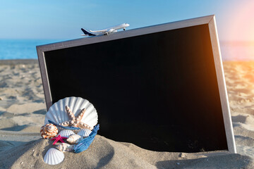 Shells pattern. Globe, seashell, airplane and starfish near black desk on sea beach in sunny day. Copy space of summer vacation and business travel concept.