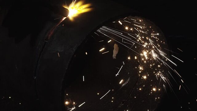 A welder cuts metal pipe by hand cutting torch with sparks