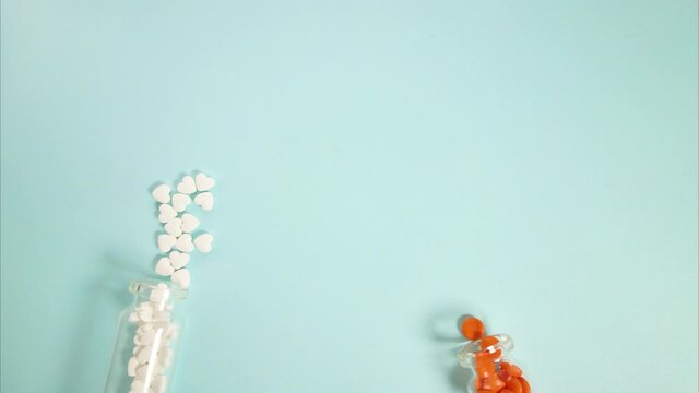 White and orange tablets are poured from one jar to another. The tablets are poured out of the glass bottle. Stop motion video footage.