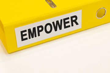The word empower on a white background with a yellow folder. Business concept