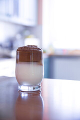 A cup of Korean coffee with milk and foam on the background of a kitchen interior