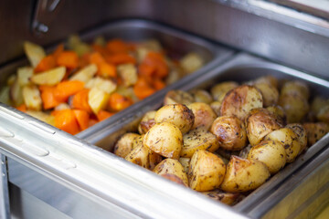 Oven baked potatoes and other vegetables. Vegetarian food. Healthy catering service buffet table at...