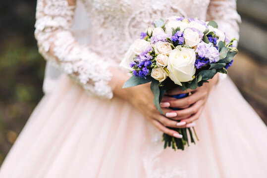 Luxurious wedding bouquet in the hands of the bride in a beautiful white dress, vertical photo