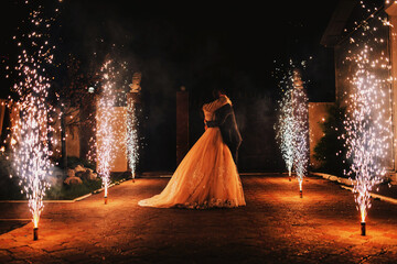 Newlyweds kiss on the background of a pyrotechnic show, fireworks fountains