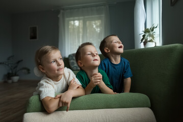 Fototapeta premium Beautiful children lying on the couch at home looking out the window.