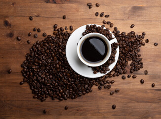 Coffee beans and cup of coffee on old wooden table.