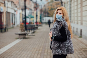 A beautiful woman wears a medical face mask to avoid the spread of coronavirus, autumn, portrait, closeup