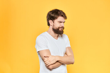 Bearded man in a white T-shirt gestures with his hands emotions studio yellow background