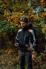 A young man uses a military compass for orientation in nature, talking on the phone, surrounded by fog.