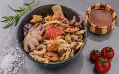 Seafood cocktail with lemon and cherry tomatoes in a beautiful plate on the background of a gray stone table top