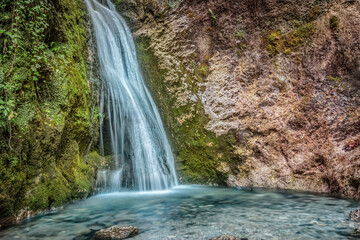 Fototapeta na wymiar Landscape view of a colorful waterfall and small basin at bottom. Cerinski vir, Samoborsko gorje, Croatia.