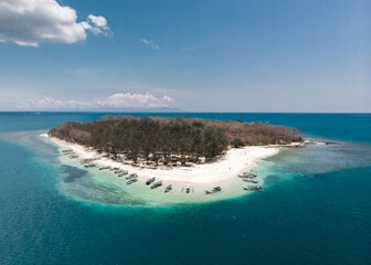 Aerial drone picture of Gili Nanggu, a remote tropical island close to Lombok, West Nusa Tenggara, Indonesia surrounded by coral reef. Traditional indonesian boats ankering on the beach.